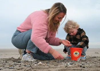 moeder en zoon verzamelen 100 schelpen in een emmer.